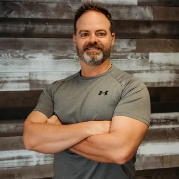 A man with his arms crossed in front of a wall.