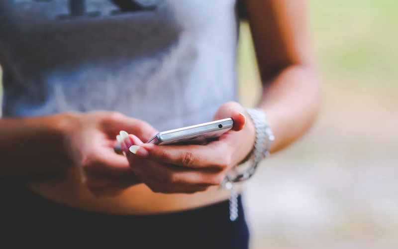 A woman holding her cell phone in both hands.