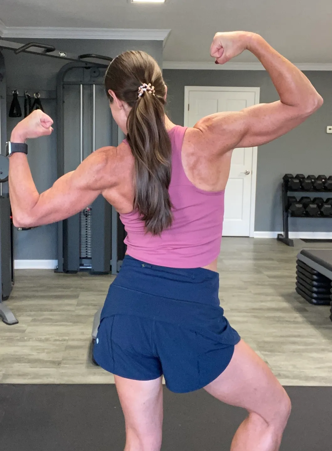 A woman is flexing her muscles in the gym.